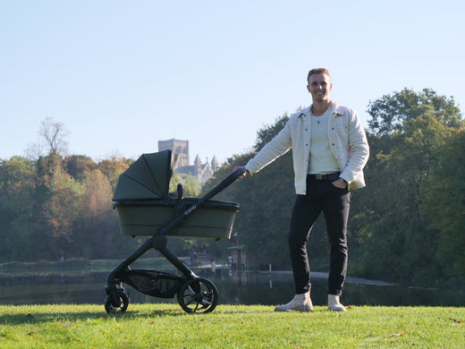 Man standing in front of lake with the iCandy peach 7 in ivy in carrycot mode