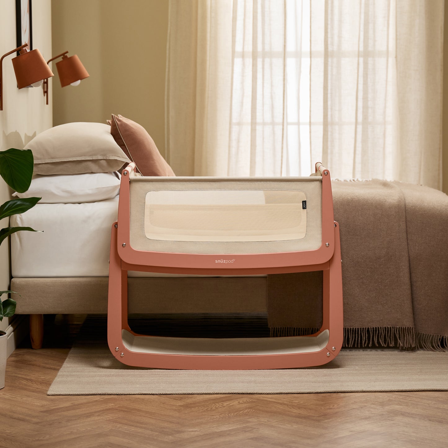 A Terracotta Snuzpod5 bedside crib designed for infants, showcasing a modern and safe sleeping environment.