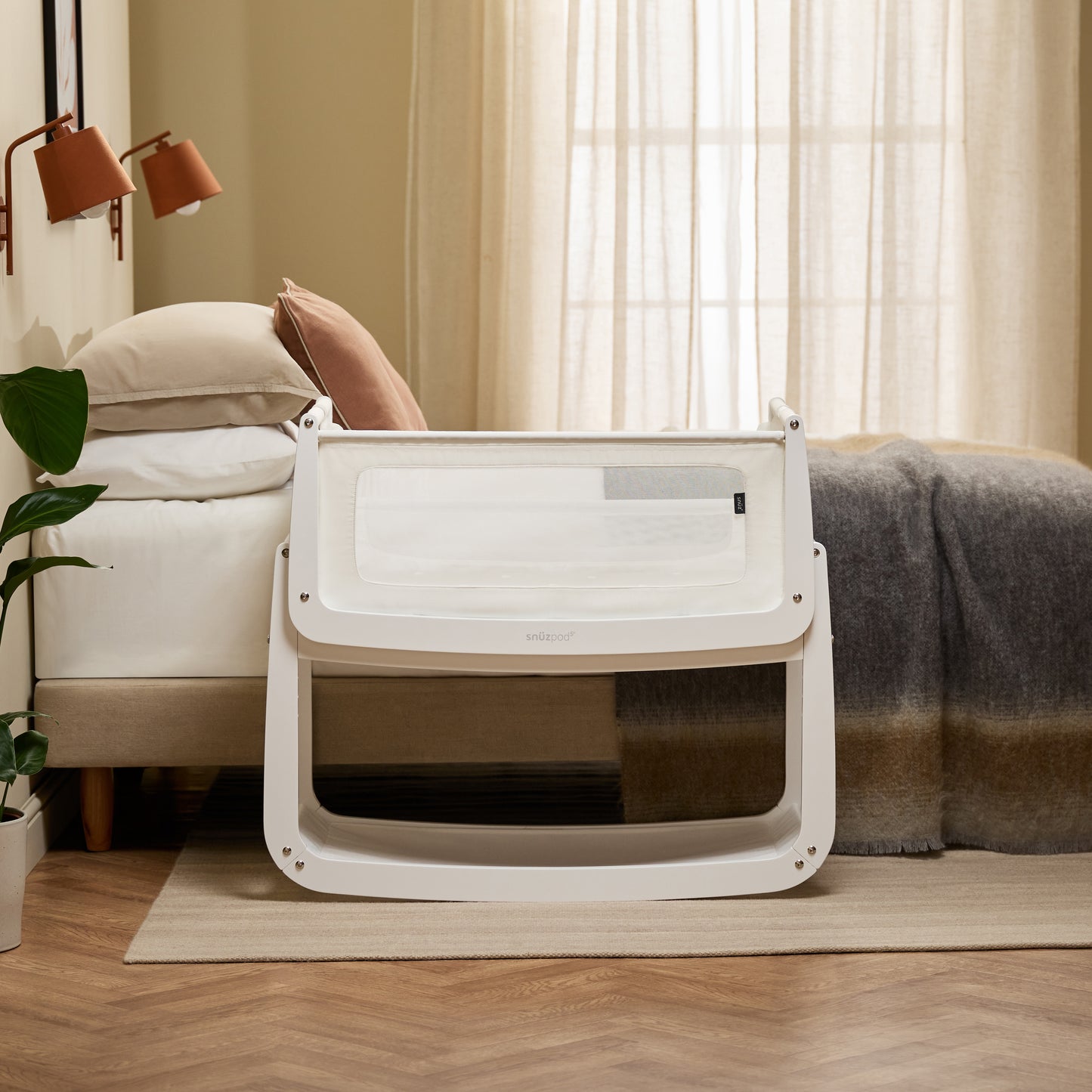 A White Snuzpod5 bedside crib designed for infants, showcasing a modern and safe sleeping environment.