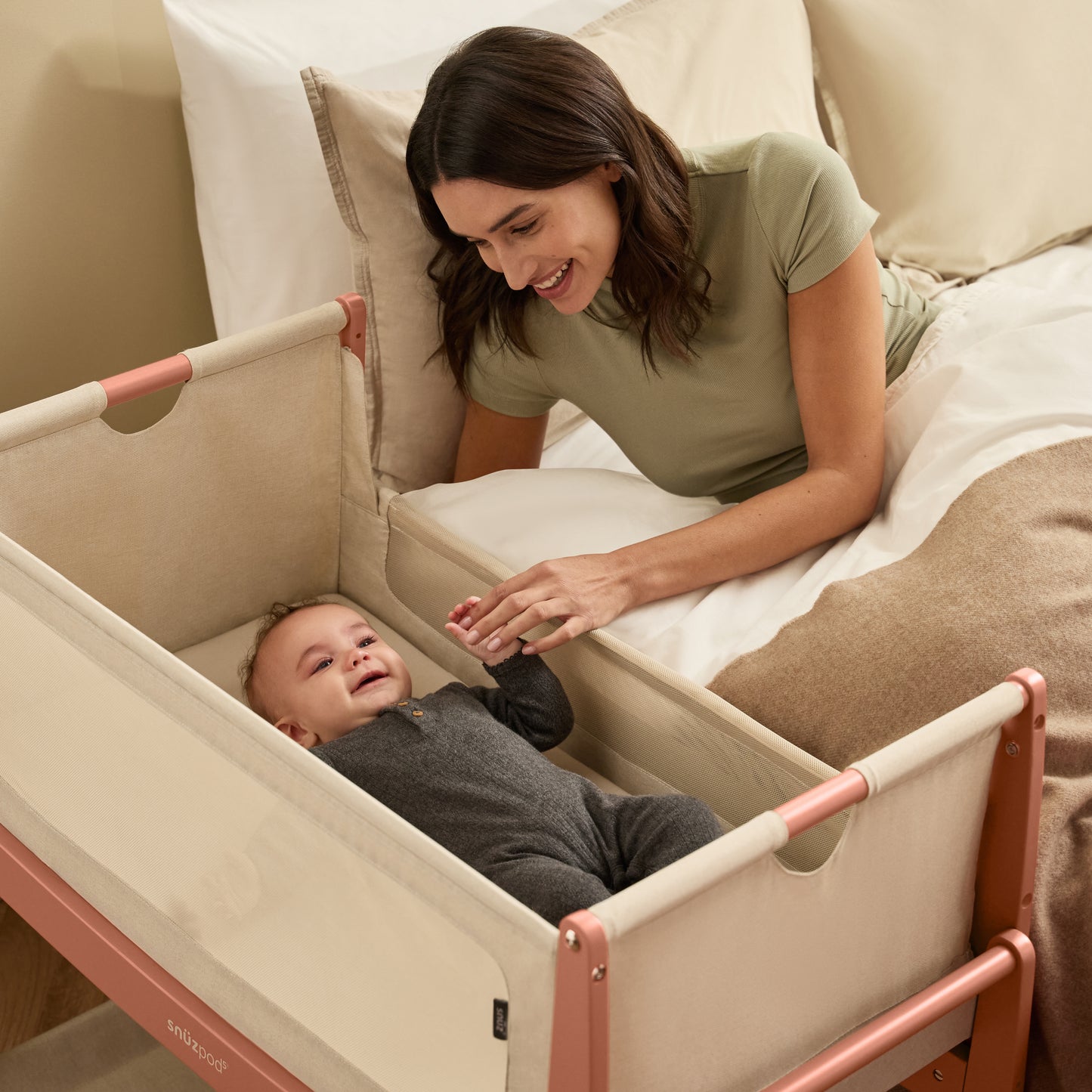 A Terracotta Snuzpod5 bedside crib designed for infants, showcasing a modern and safe sleeping environment.