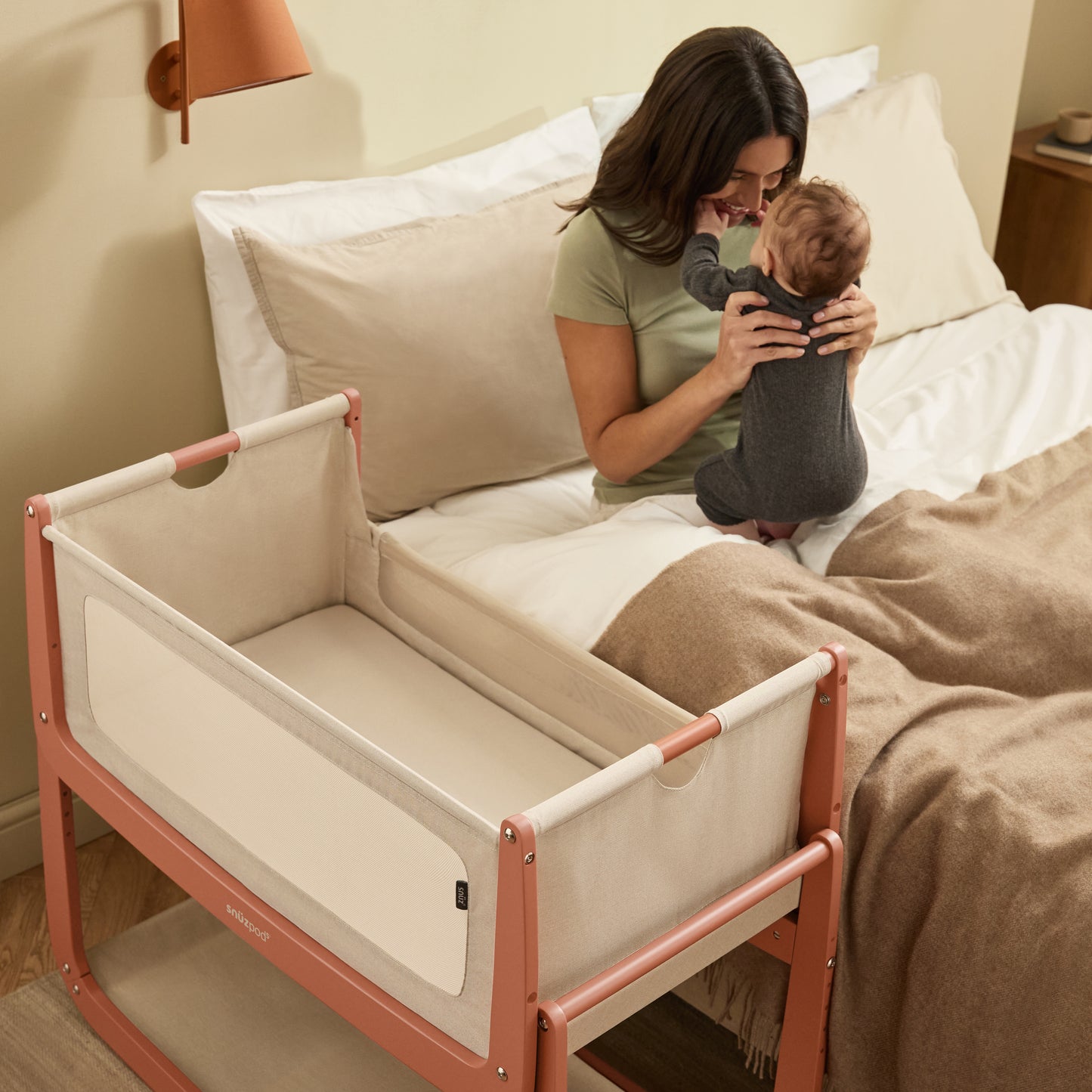 A Terracotta Snuzpod5 bedside crib designed for infants, showcasing a modern and safe sleeping environment.