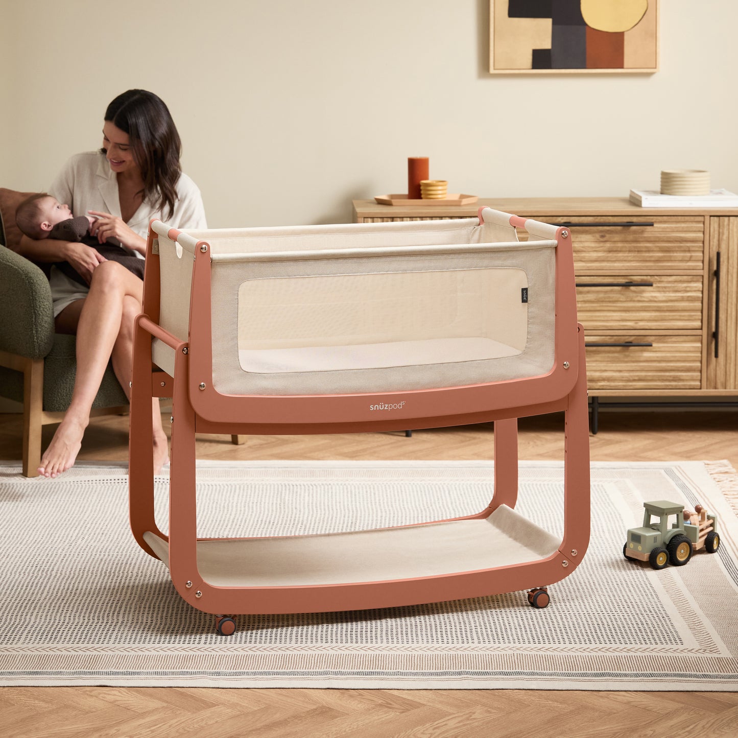 A Terracotta Snuzpod5 bedside crib designed for infants, showcasing a modern and safe sleeping environment.