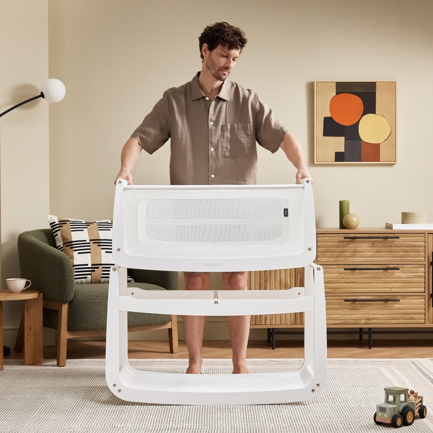 A White Snuzpod5 bedside crib designed for infants, showcasing a modern and safe sleeping environment.