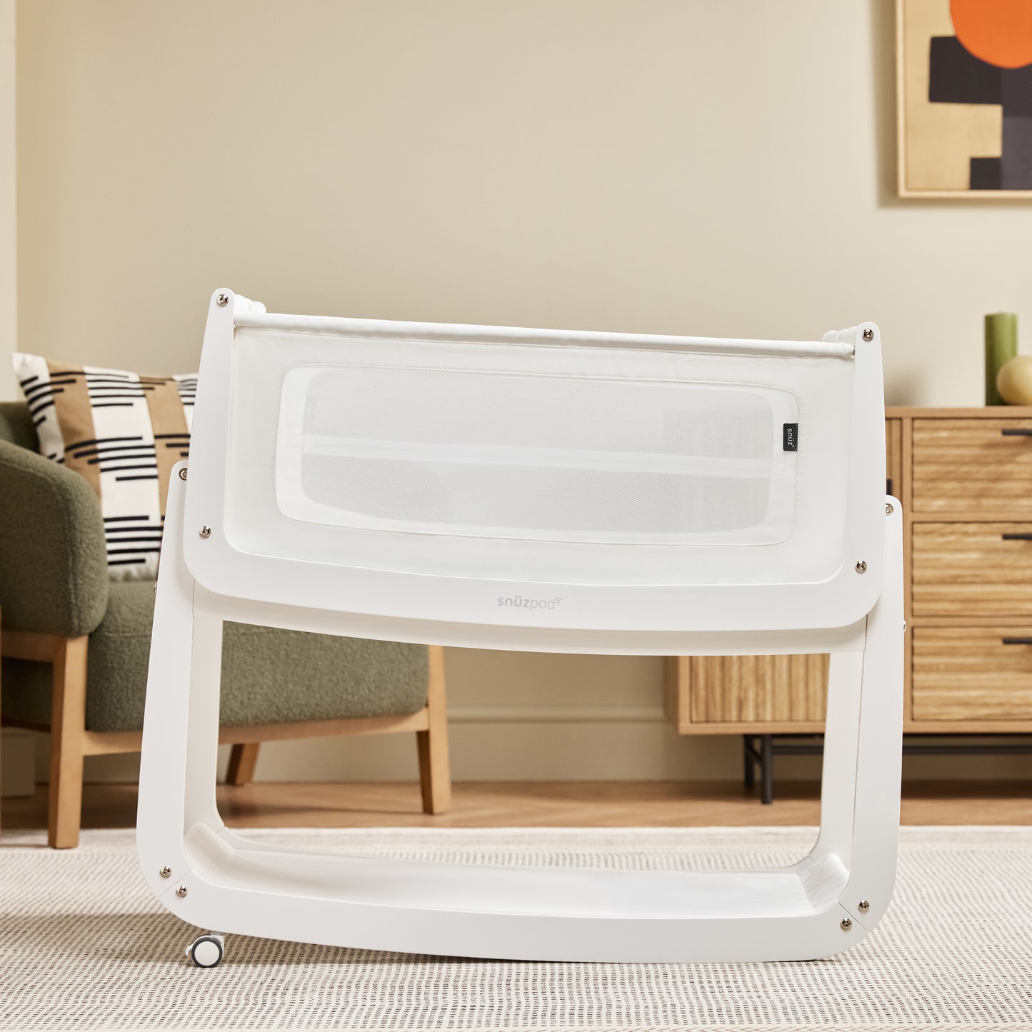 A White Snuzpod5 bedside crib designed for infants, showcasing a modern and safe sleeping environment.