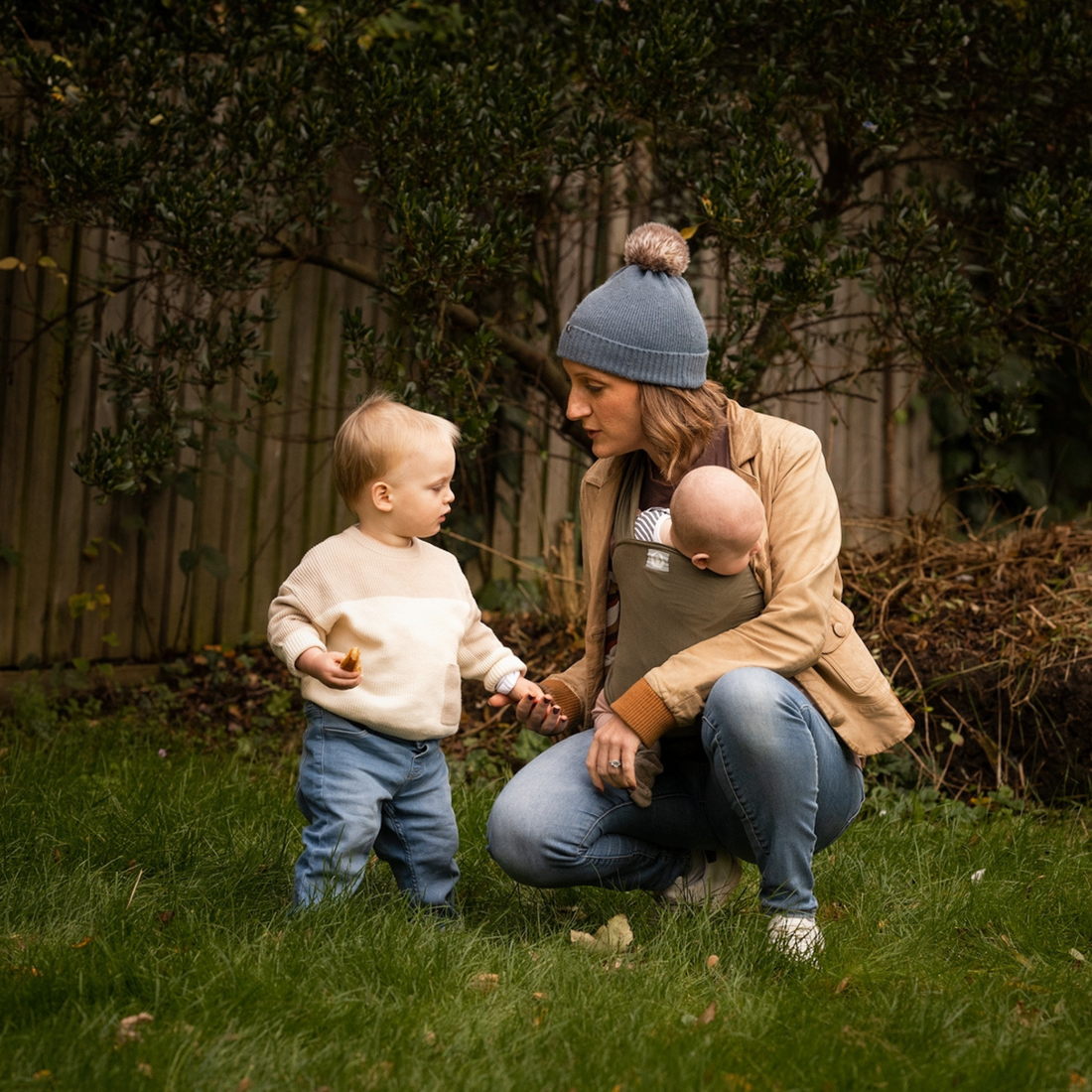 gaia baby wrap featuring mum with baby in wrap. knelt down talking to there toddler