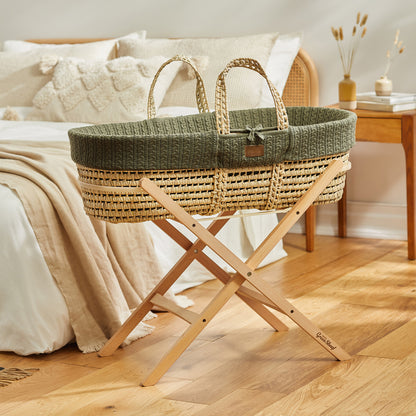  A baby's Juniper Moses basket on a wooden stand, situated in front of a double bed