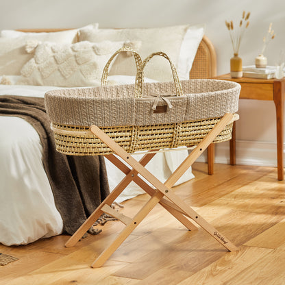  A baby's Truffle Moses basket on a wooden stand, situated in front of a double bed