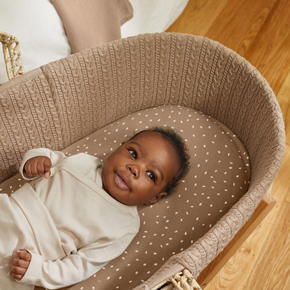 Truffle Moses basket with baby sitting comfortably on top.