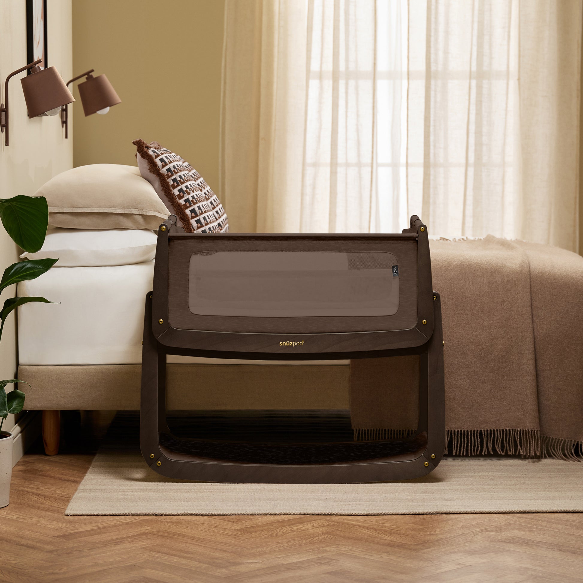 A choclate brown Snuzpod5 bedside crib designed for infants, showcasing a modern and safe sleeping environment.