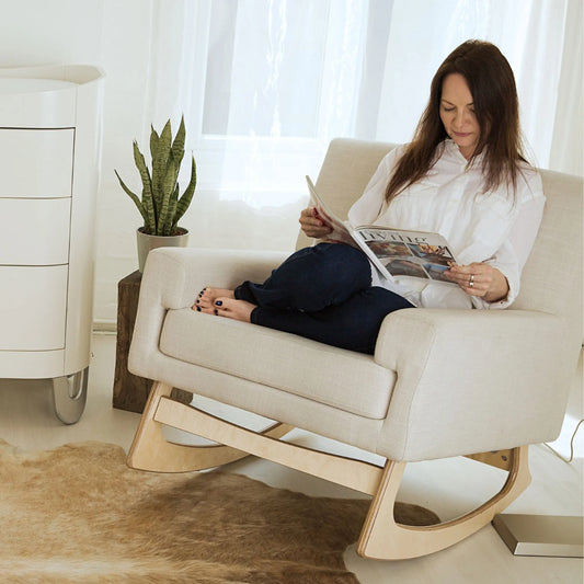 Fabric rocking chair featuring a lumbar cushion and low arms, designed for comfort while feeding a baby.