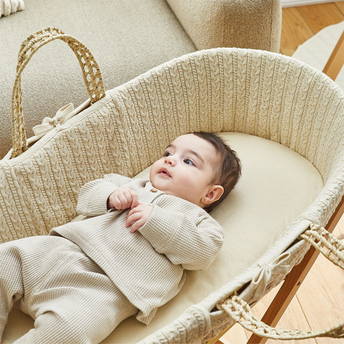 Linen Moses basket with baby sitting comfortably on top.