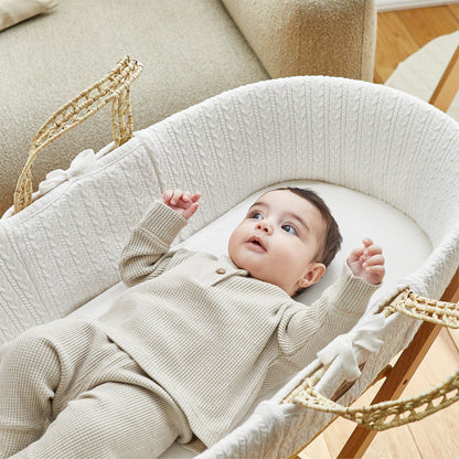 White Moses basket with baby sitting comfortably on top.