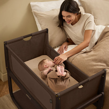 A choclate brown Snuzpod5 bedside crib designed for infants, showcasing a modern and safe sleeping environment.