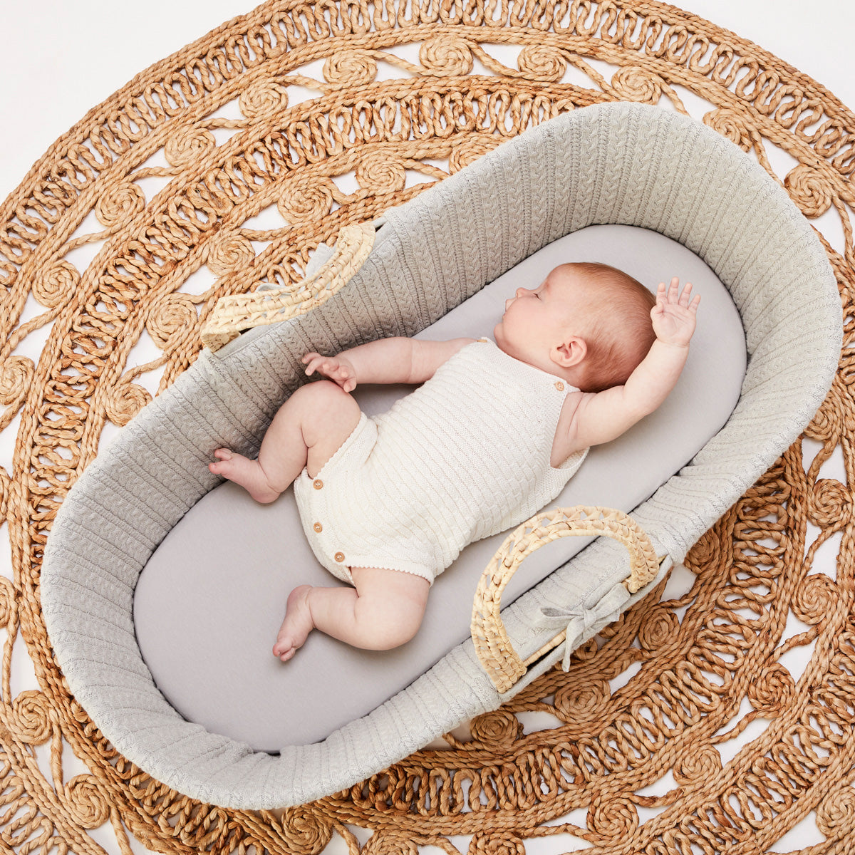 Baby sleeping on protector in linen moses basket