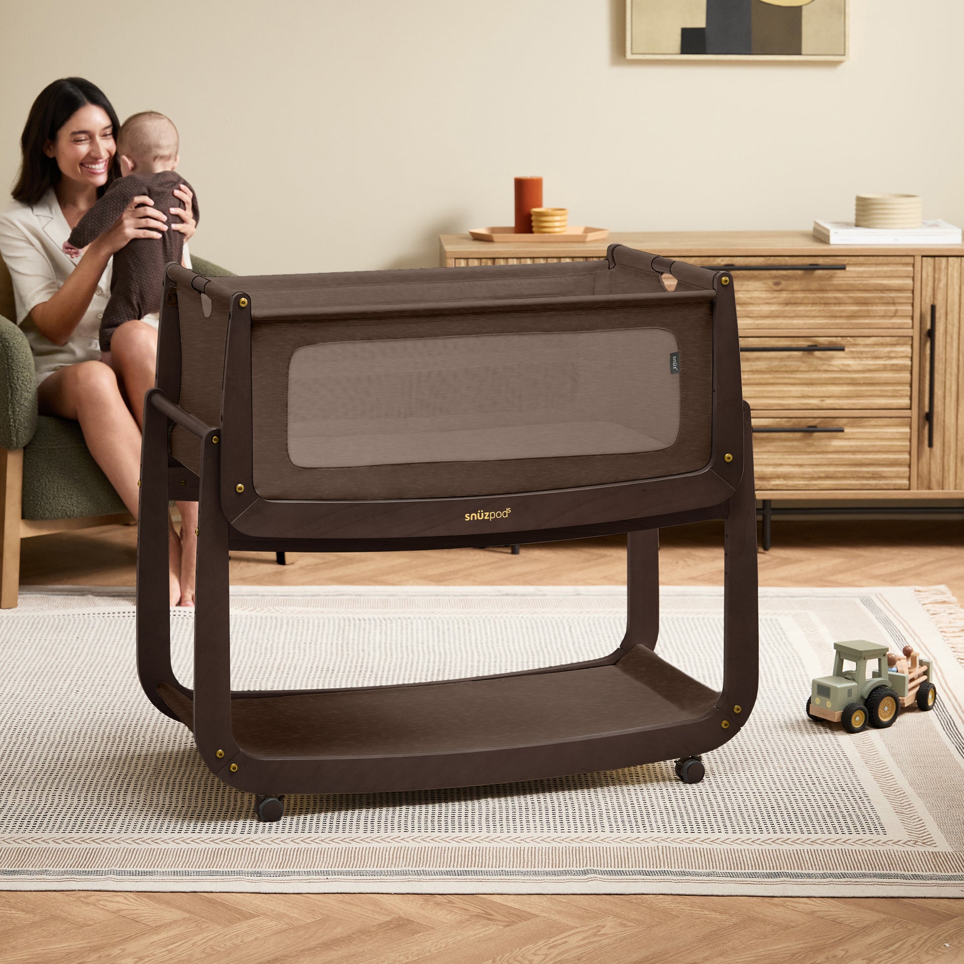 A choclate brown Snuzpod5 bedside crib designed for infants, showcasing a modern and safe sleeping environment.