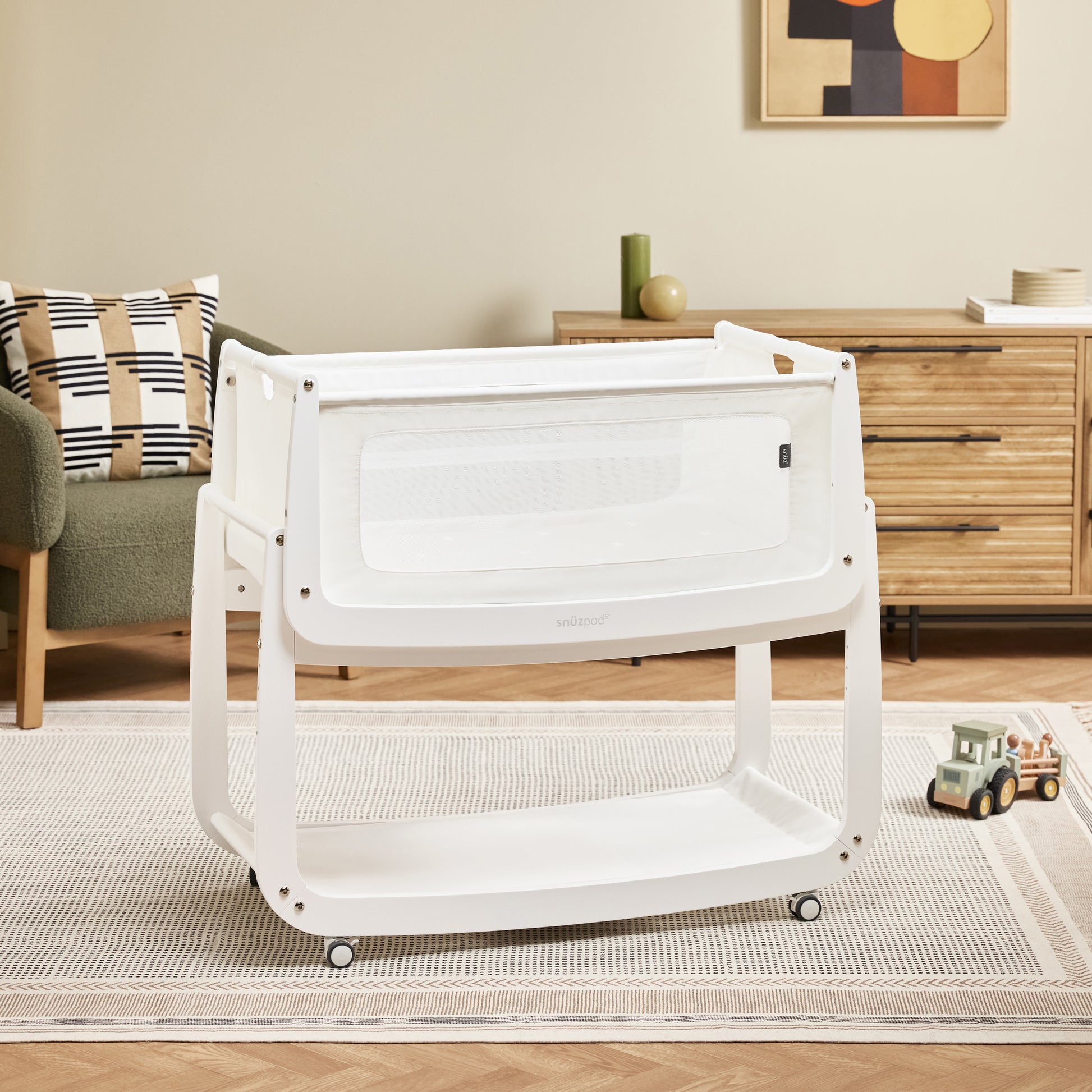 A White Snuzpod5 bedside crib designed for infants, showcasing a modern and safe sleeping environment.