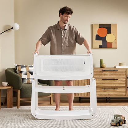 A White Snuzpod5 bedside crib designed for infants, showcasing a modern and safe sleeping environment.