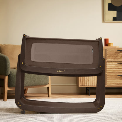 A choclate brown Snuzpod5 bedside crib designed for infants, showcasing a modern and safe sleeping environment.