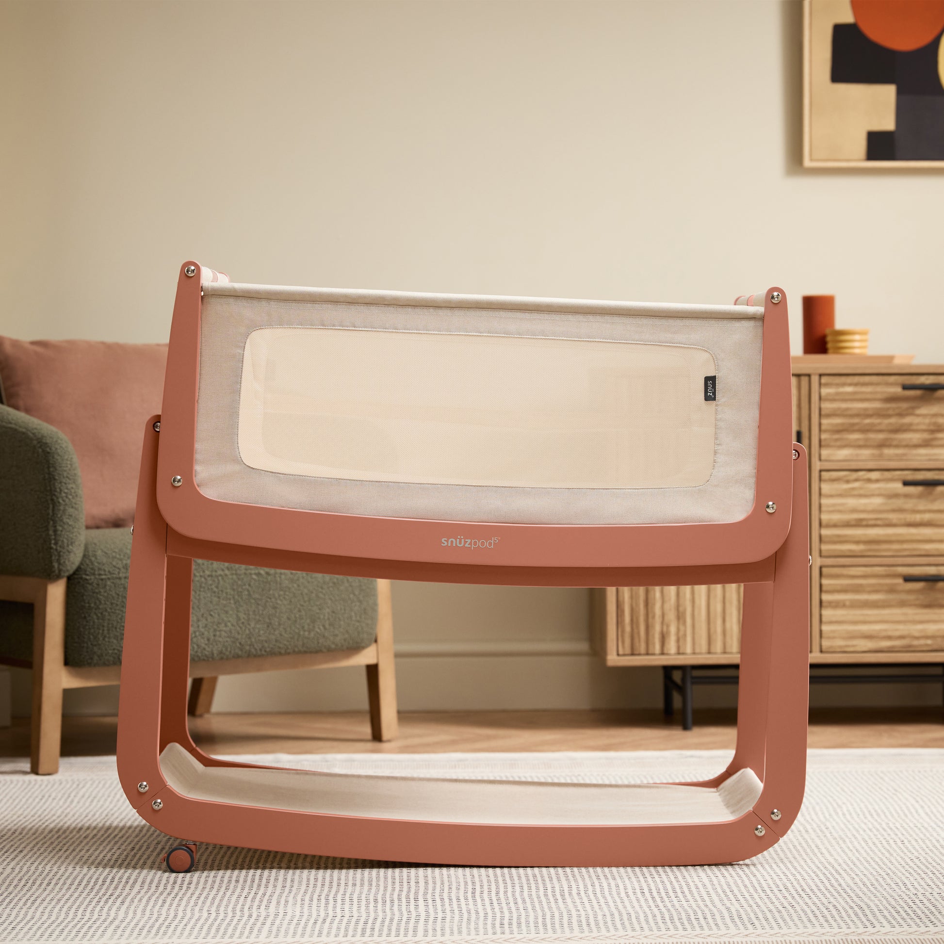 A Terracotta Snuzpod5 bedside crib designed for infants, showcasing a modern and safe sleeping environment.