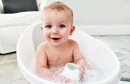 Baby playing with Shnuggle wishy bath toy in the bath