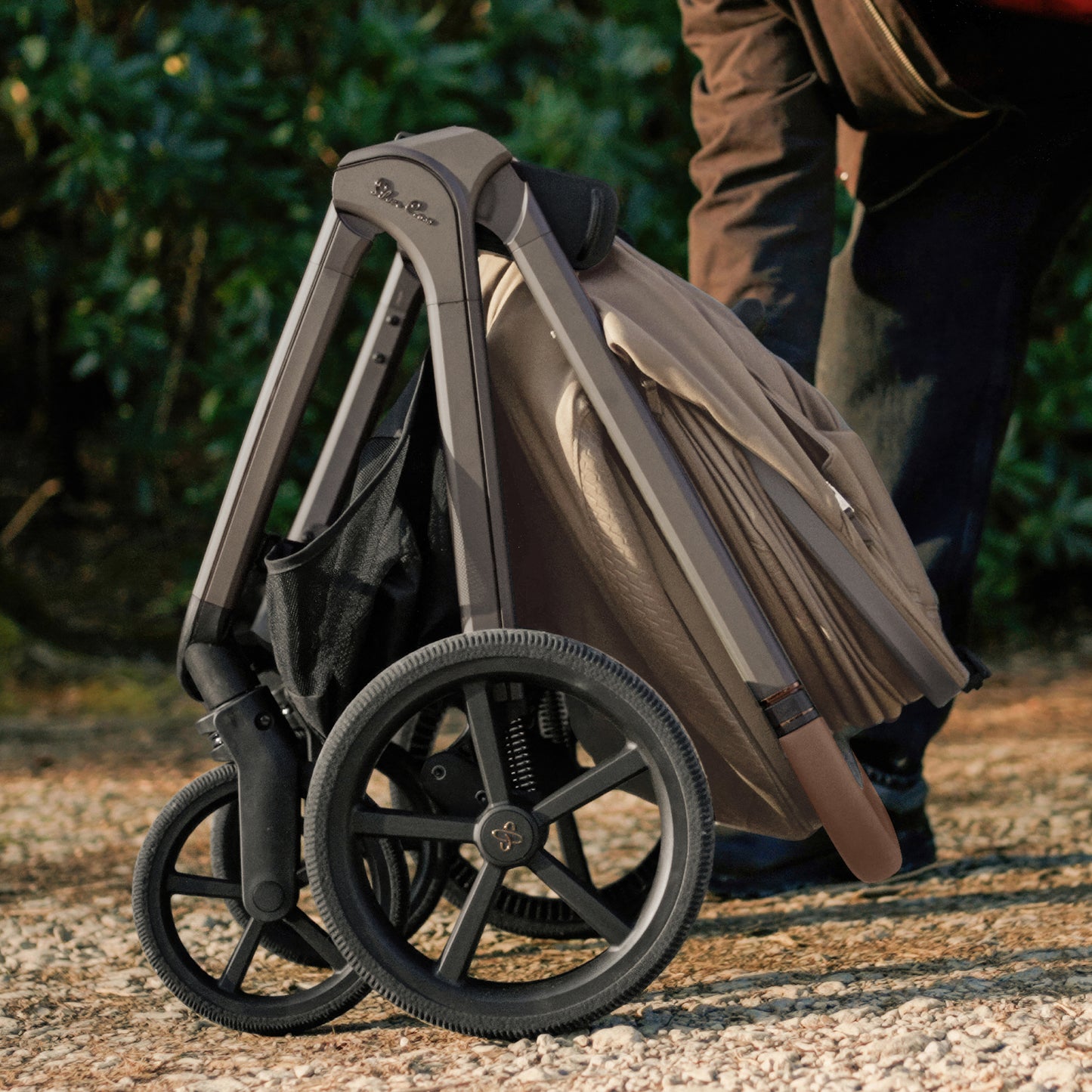 A multi-item silver cross cove 2 travel system set displayed on white pedestals against a white background. The set includes a beige and black stroller, a matching bassinet, a seat, a car seat, a footmuff, a travel bag, a baby backpack, and accessories.