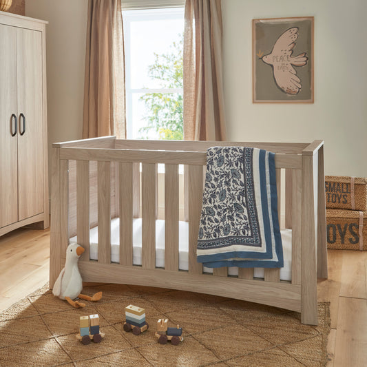 The Isla Cot Bed, featuring an ash finish, is a stylish addition to any nursery.