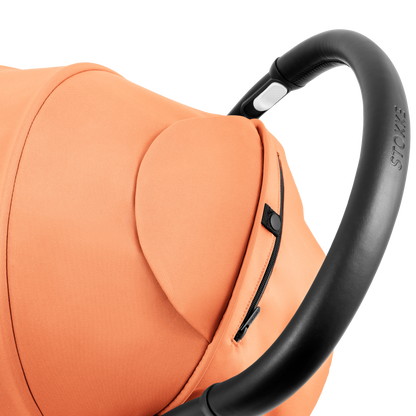 A compact yoyo 5 stroller with a peach orange canopy and seat lining, a black frame, and black wheels, shown on a plain white background.