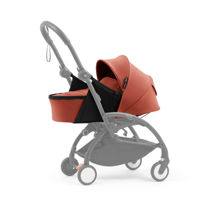 A yoyo stroller bassinet attachment set in terracotta orange and black, shown mounted on a stroller frame against a solid white background.