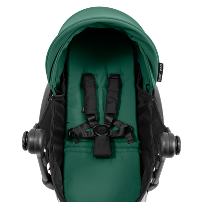 A yoyo stroller bassinet attachment set in dark green and black, shown mounted on a stroller frame against a solid white background.