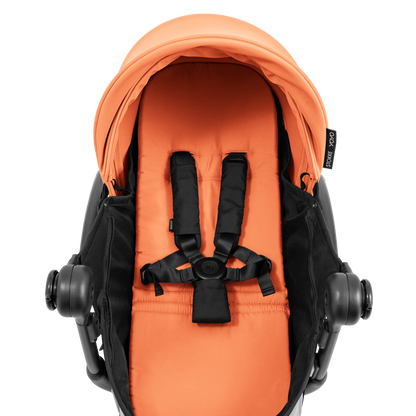 A yoyo stroller bassinet attachment set in orange and black, shown mounted on a stroller frame against a solid white background.