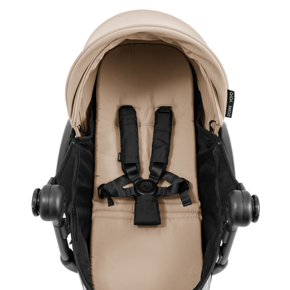 A yoyo stroller bassinet attachment set in beige and black, shown mounted on a stroller frame against a solid white background.
