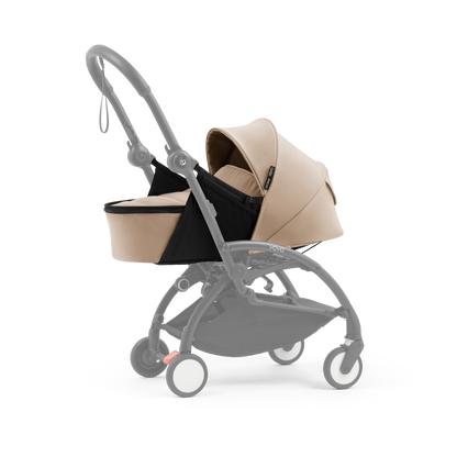 A yoyo stroller bassinet attachment set in beige and black, shown mounted on a stroller frame against a solid white background.