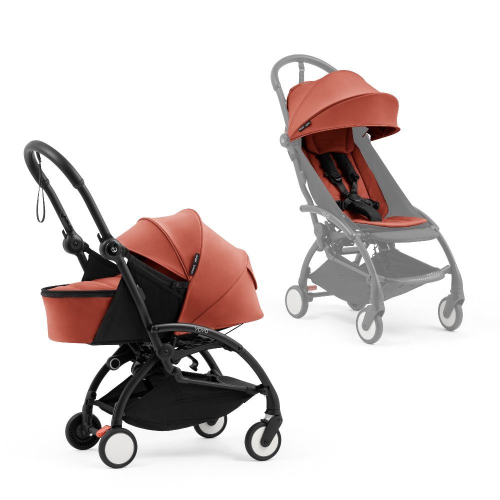 A black stroller newborn travel system shown in terracotta, with a stroller behind it to demonstrate compatibility, on a clean white background.