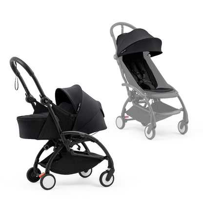 A black stroller newborn travel system shown in black, with a stroller behind it to demonstrate compatibility, on a clean white background.
