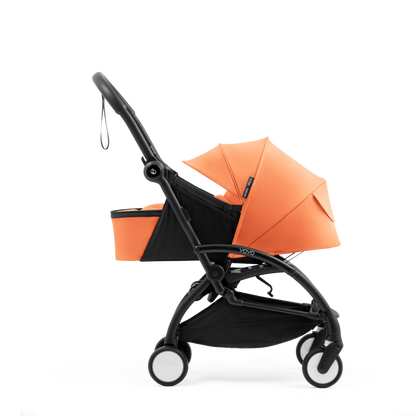 A yoyo stroller bassinet attachment set in orange and black, shown mounted on a stroller frame against a solid white background.