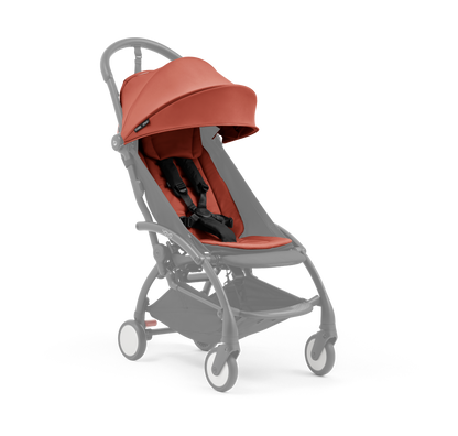 A compact baby stroller with a terracotta canopy and terracotta padded seat, with a blacked out chassis, shown on a plain white background.