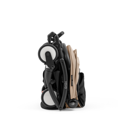 A compact yoyo 5 stroller with a beige canopy and seat lining, a black frame, and black wheels, shown on a plain white background.