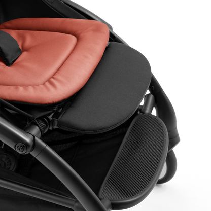 A compact yoyo 5 stroller with a rust-orange canopy and seat lining, a black frame, and black wheels, shown on a plain white background.