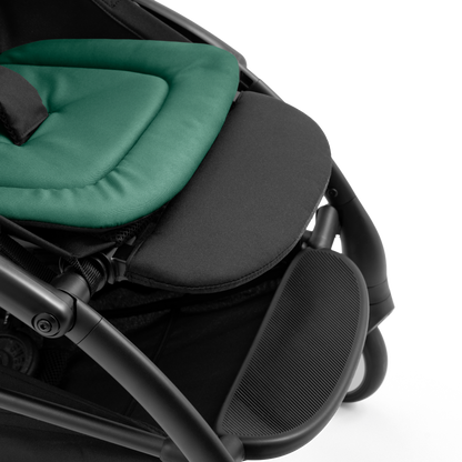 A compact yoyo 5 stroller with a green canopy and seat lining, a black frame, and black wheels, shown on a plain white background.