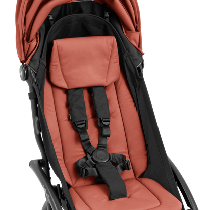 A compact yoyo 5 stroller with a rust-orange canopy and seat lining, a black frame, and black wheels, shown on a plain white background.
