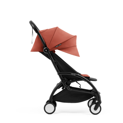 A compact yoyo 5 stroller with a rust-orange canopy and seat lining, a black frame, and black wheels, shown on a plain white background.