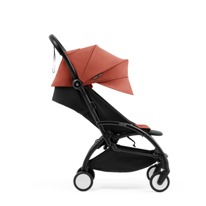 A compact yoyo 5 stroller with a rust-orange canopy and seat lining, a black frame, and black wheels, shown on a plain white background.