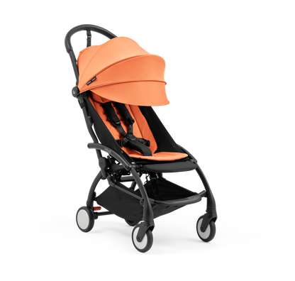 A compact yoyo 5 stroller with a peach orange canopy and seat lining, a black frame, and black wheels, shown on a plain white background.