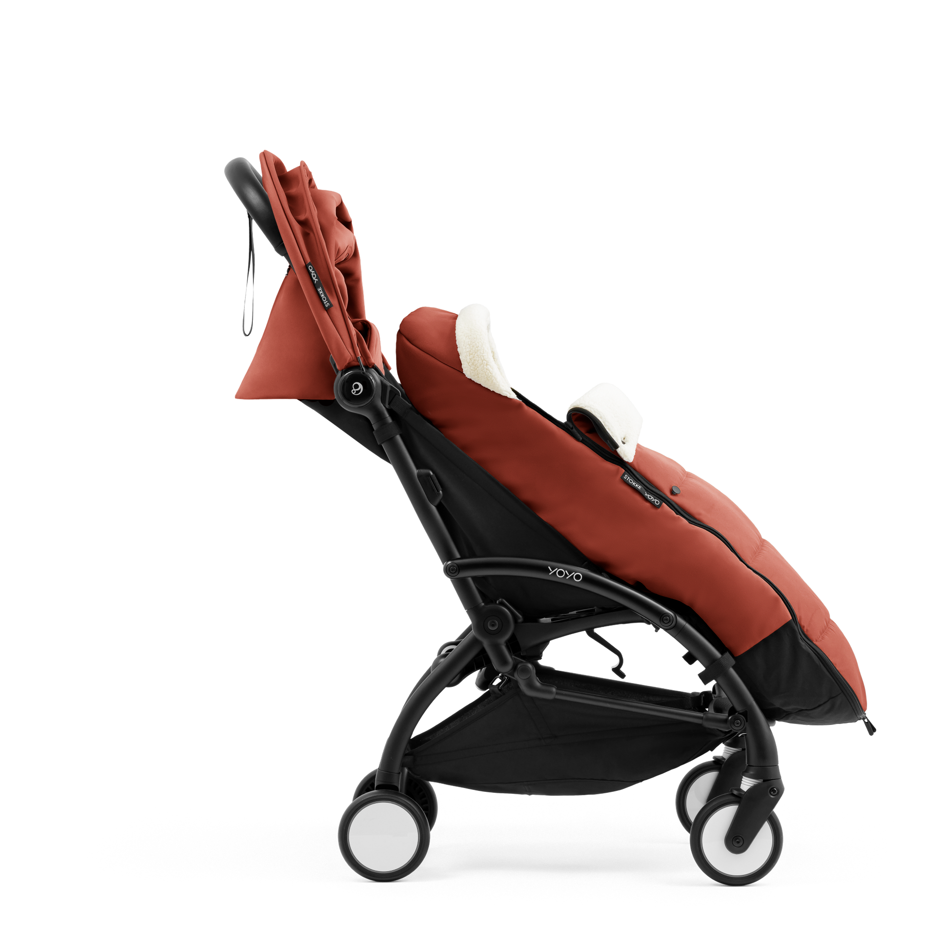 A stroller with a rust-colored padded footmuff, cream fleece lining, and a black frame, shown from the front on a white background.