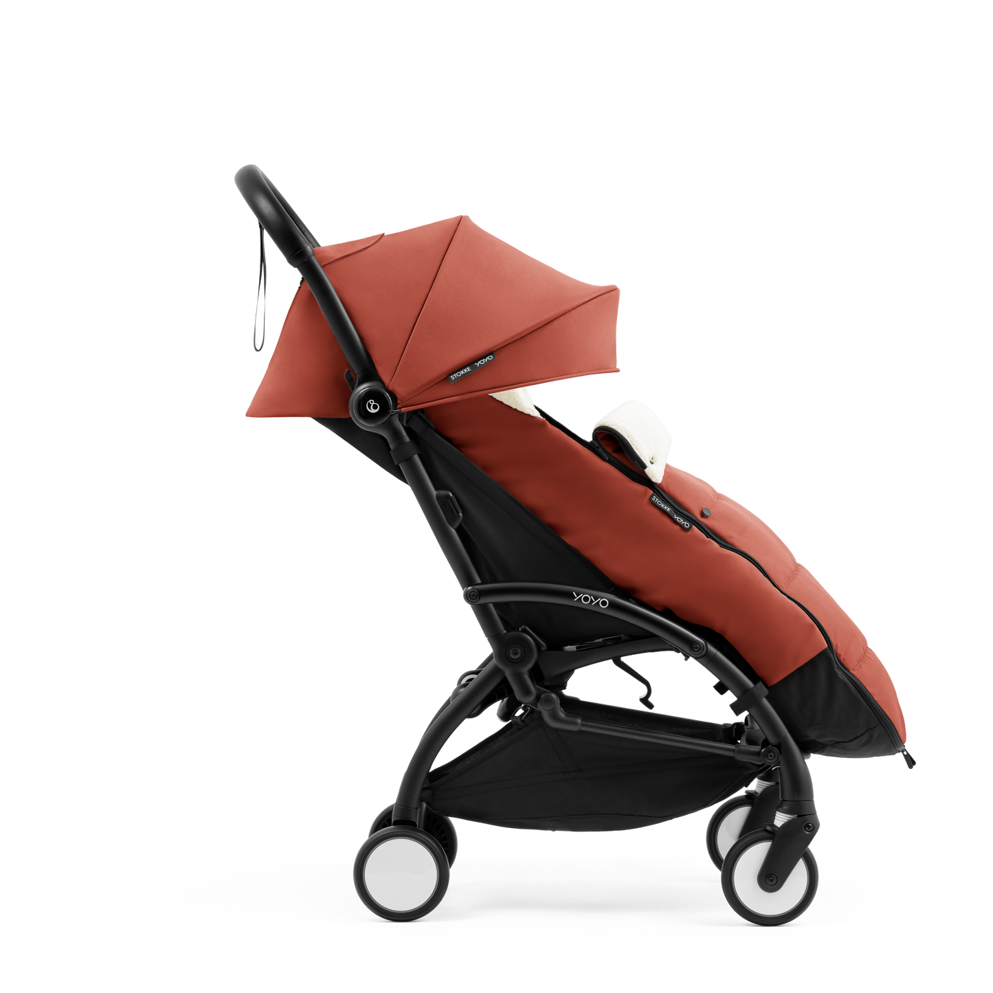 A stroller with a rust-colored padded footmuff, cream fleece lining, and a black frame, shown from the front on a white background.