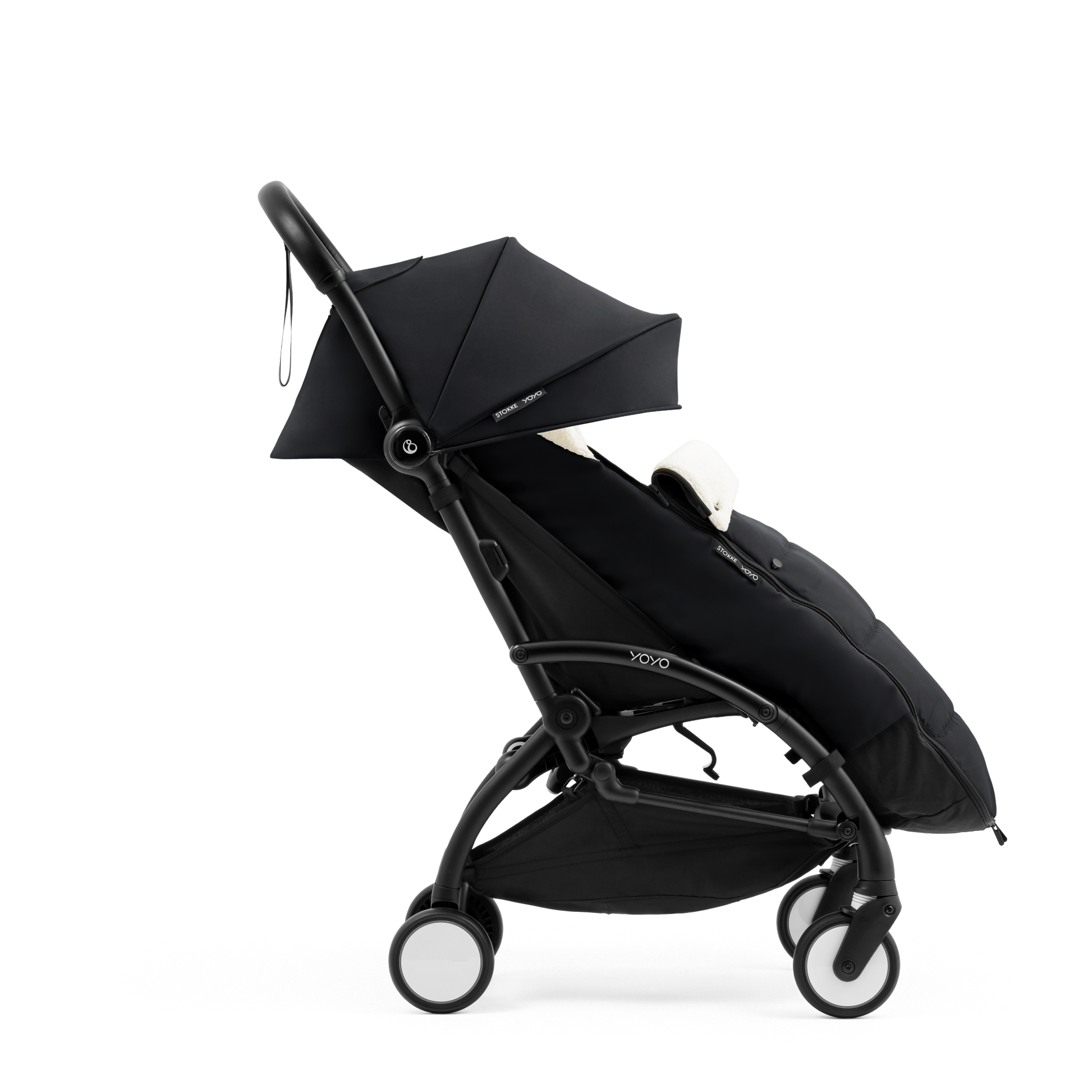 A stroller with a black colored padded footmuff, cream fleece lining, and a black frame, shown from the front on a white background.