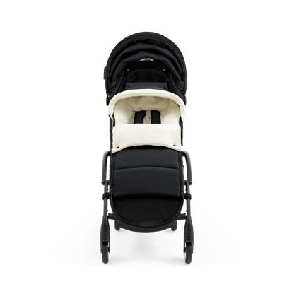 A stroller with a black colored padded footmuff, cream fleece lining, and a black frame, shown from the front on a white background.