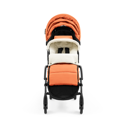 A stroller with a orange colored padded footmuff, cream fleece lining, and a black frame, shown from the front on a white background.