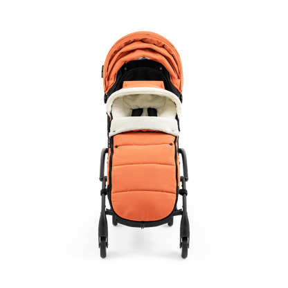 A stroller with a orange colored padded footmuff, cream fleece lining, and a black frame, shown from the front on a white background.
