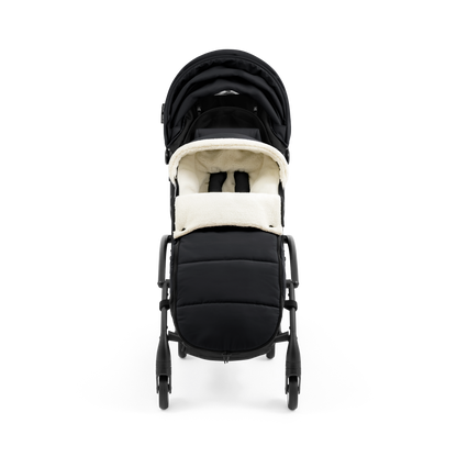 A stroller with a black colored padded footmuff, cream fleece lining, and a black frame, shown from the front on a white background.